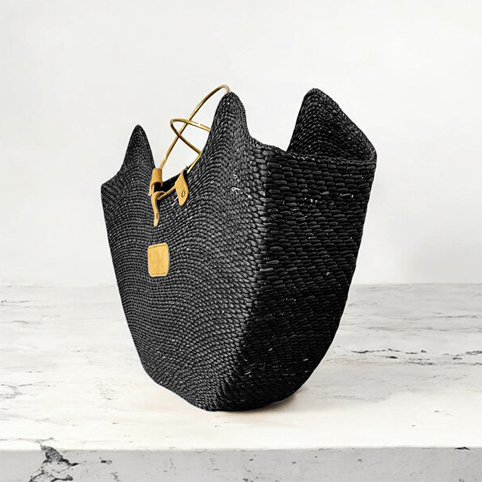Black woven bag with gold accents on a white surface