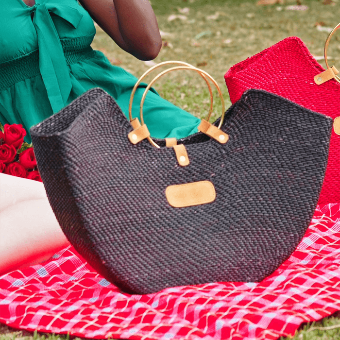 Black woven handbag with gold accents on a red checkered blanket