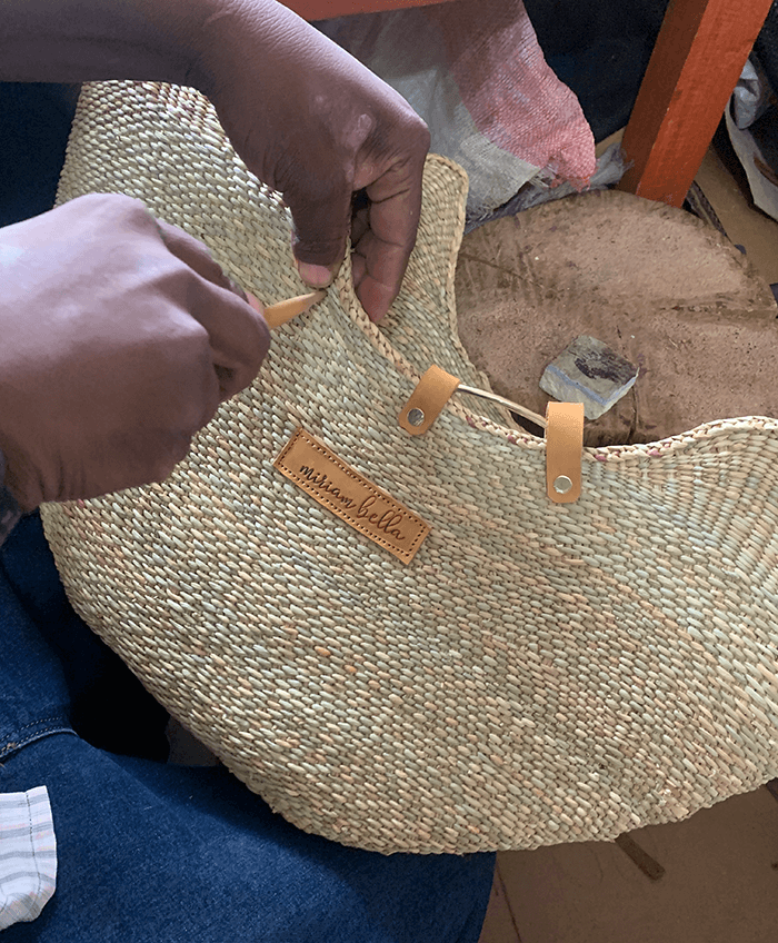 Person holding a woven bag with a visible brand label.
