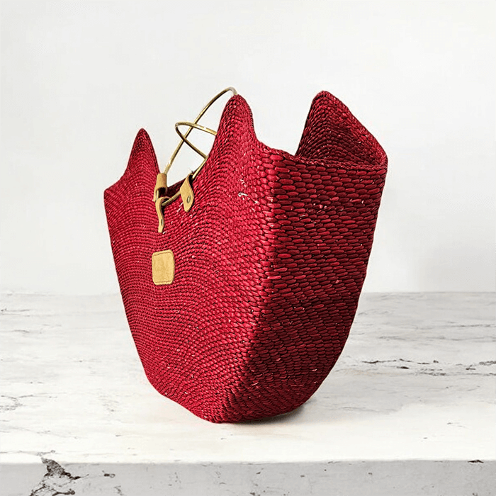 Red woven bag with gold accents on a white surface