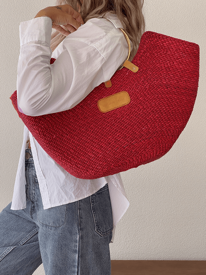 Person wearing a red woven bag over one shoulder against a plain background