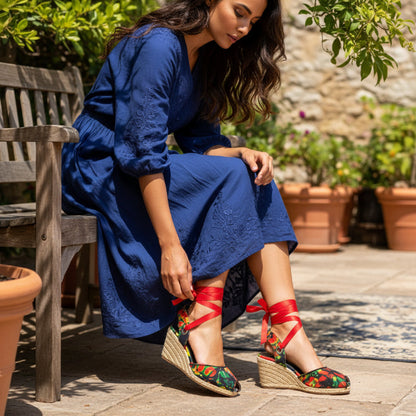 Woman in a blue dress sitting on a bench wearing colorful sandals with red straps.