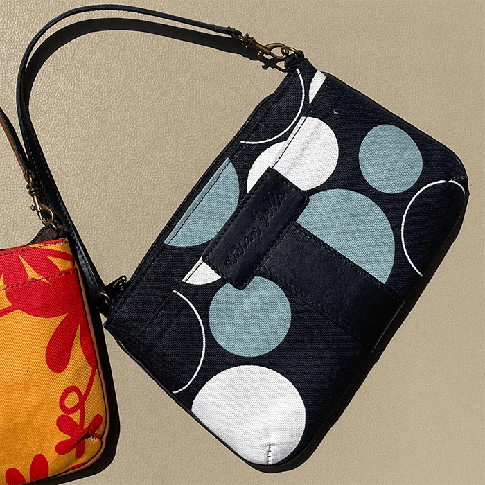 Black pouch with blue and white circular patterns on a beige background