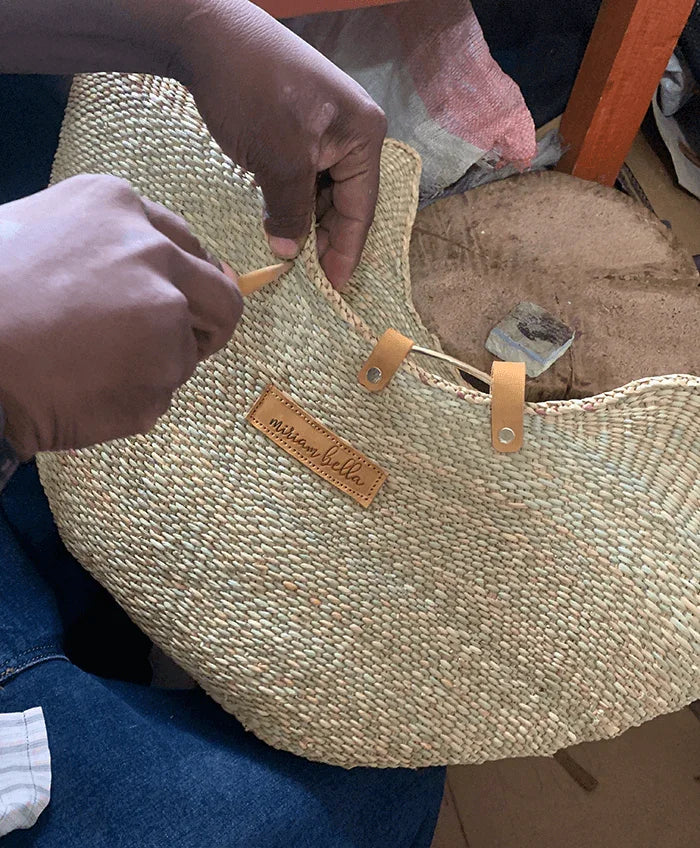 Person holding a woven bag with a visible brand label.