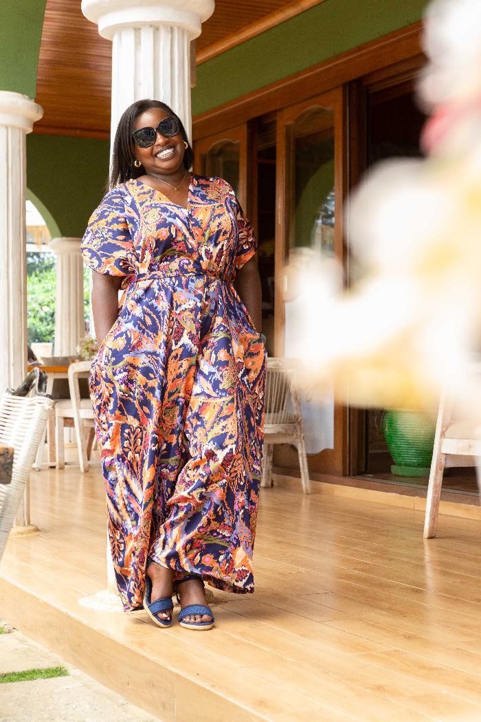 Woman in a colorful dress standing on a wooden floor with a blurred background