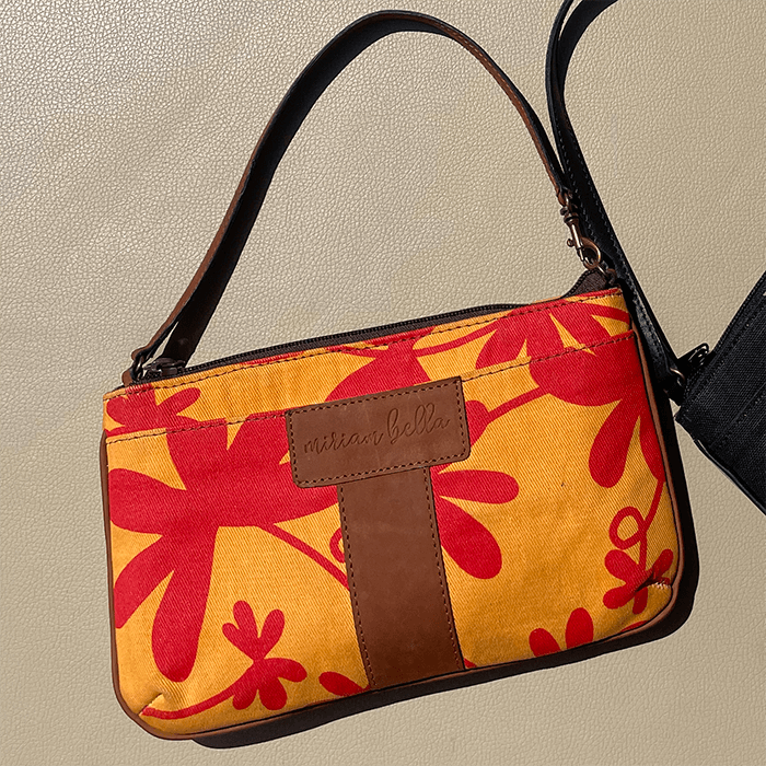 Handbag with red floral pattern and brown strap on a beige background