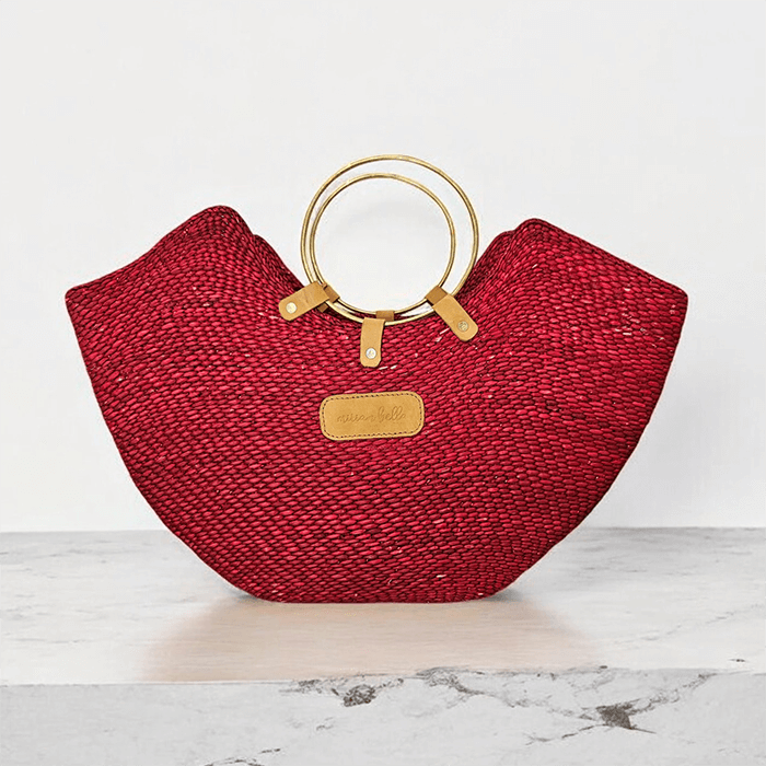 Red woven handbag with gold handles on a marble surface