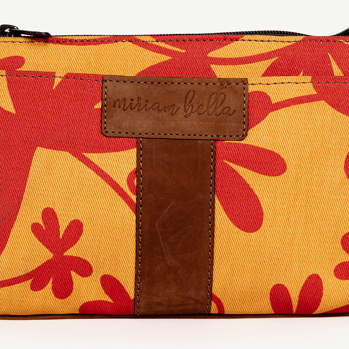 Floral-patterned pouch with a brown leather tag on a white background