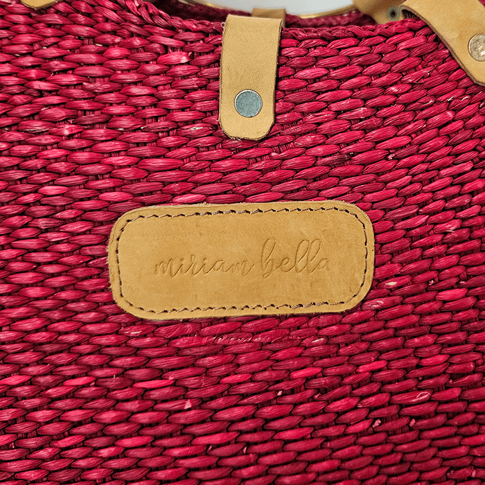 Red woven bag with a tan leather tag displaying 'miriam bella'.