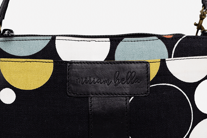 Black pouch with geometric patterns and 'arian bella' branding on a light gray background