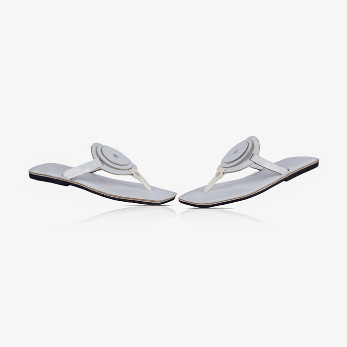 Image of a pair of white handmade leather flat sandals with a circle design produced by Australian brand Miriam Bella