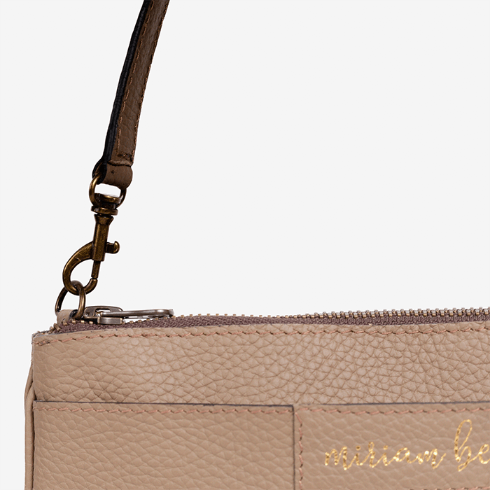 Close-up of a beige handbag with a strap and 'michael be' branding on a light gray background