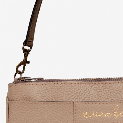 Close-up of a beige handbag with a strap and 'michael be' branding on a light gray background