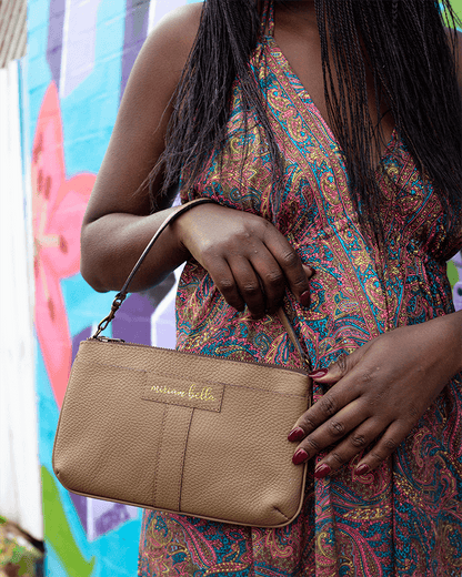 Person holding a beige handbag with a colorful dress against a vibrant background