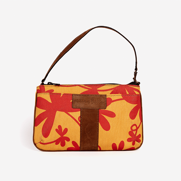 Handbag with red floral pattern and brown strap on a white background