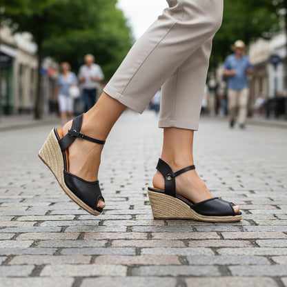 Gaia black leather closed toe espadrille wedge sandals worn while walking on a cobblestone street.