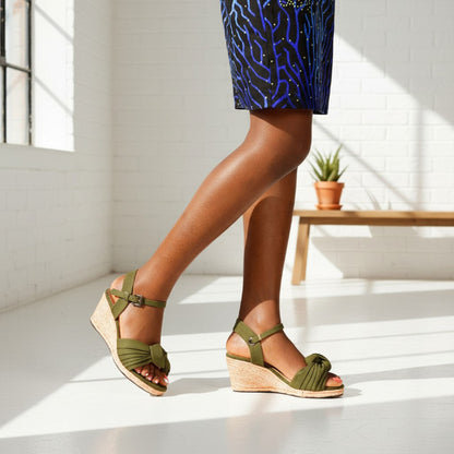 Person wearing green espadrille wedge sandals with a patterned skirt in a bright room.