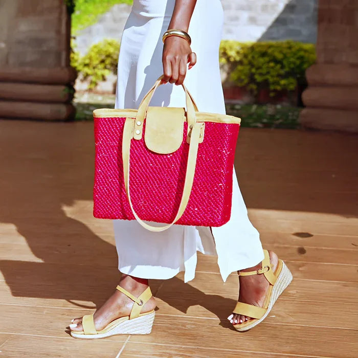 Woman wearing Gaia ochre leather open toe espadrille wedge sandals with white dress and a pink woven tote.