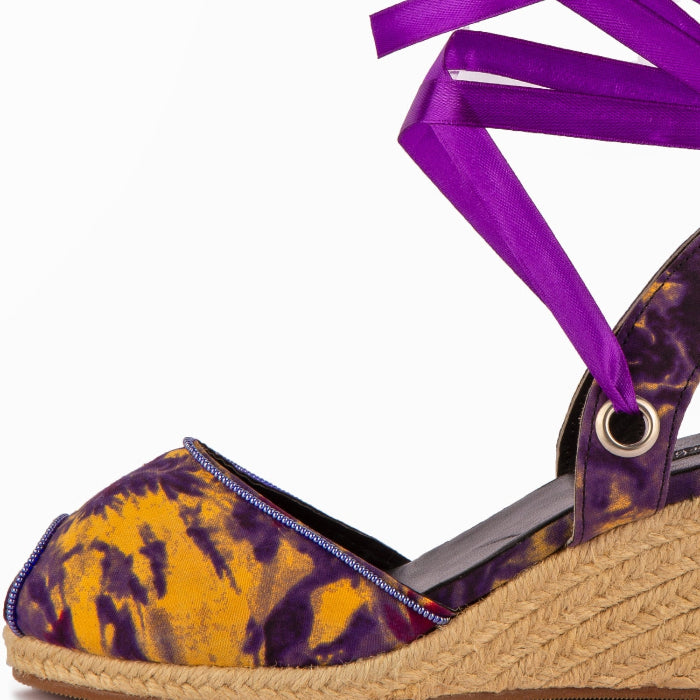 Purple and yellow espadrille wedge sandal with a purple ribbon on a white background