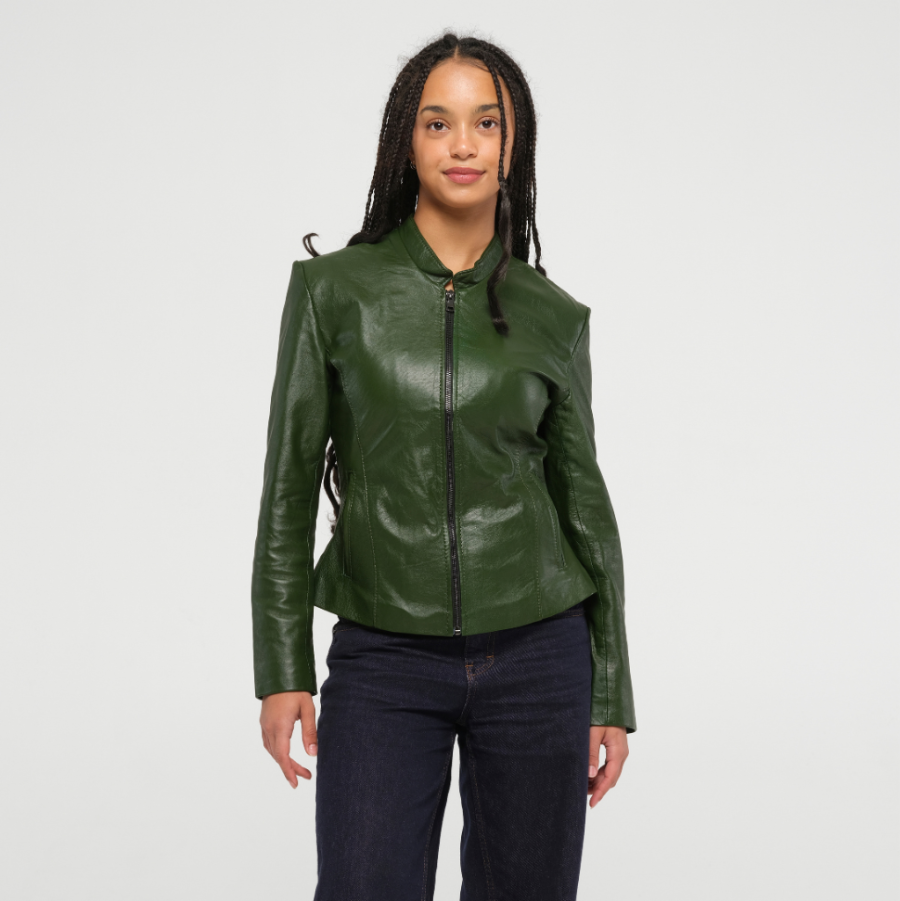 A woman modeling a dark green fitted genuine leather jacket with a front zipper, stand collar, and side tie details, paired with dark blue jeans against a light gray studio background.