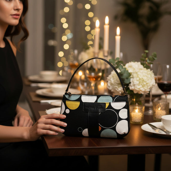 Woman holding a patterned handbag at a dinner table with candles and flowers.