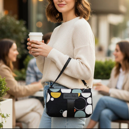 Woman holding a coffee cup and a patterned handbag in an outdoor setting