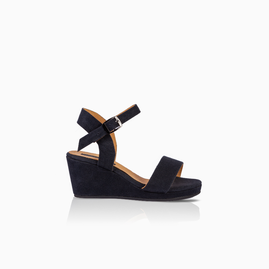 A single black wedge sandal with a wide front strap and an adjustable ankle strap with a silver buckle, shown in profile against a white background with a soft reflection.