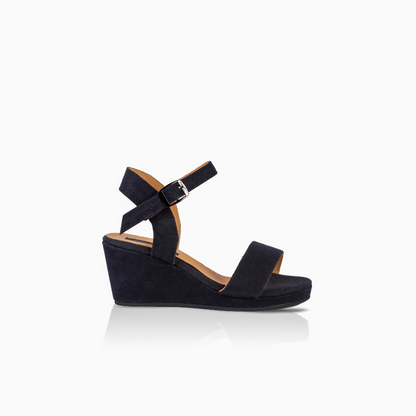 A single black wedge sandal with a wide front strap and an adjustable ankle strap with a silver buckle, shown in profile against a white background with a soft reflection.