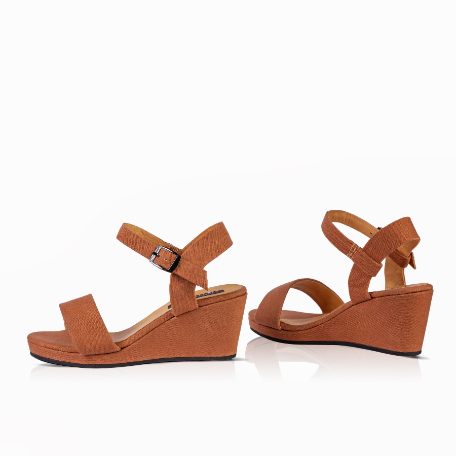 A pair of women's wedge sandals in a warm tan/cognac color, featuring a double-strap design with an ankle buckle on one sandal, shown against a plain white background.