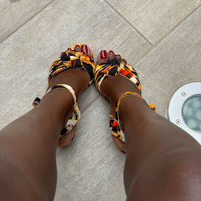 Colorful sandals worn on feet with a neutral background