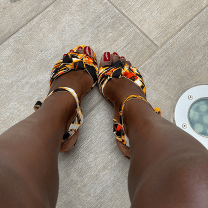 Colorful sandals worn on feet with a neutral background
