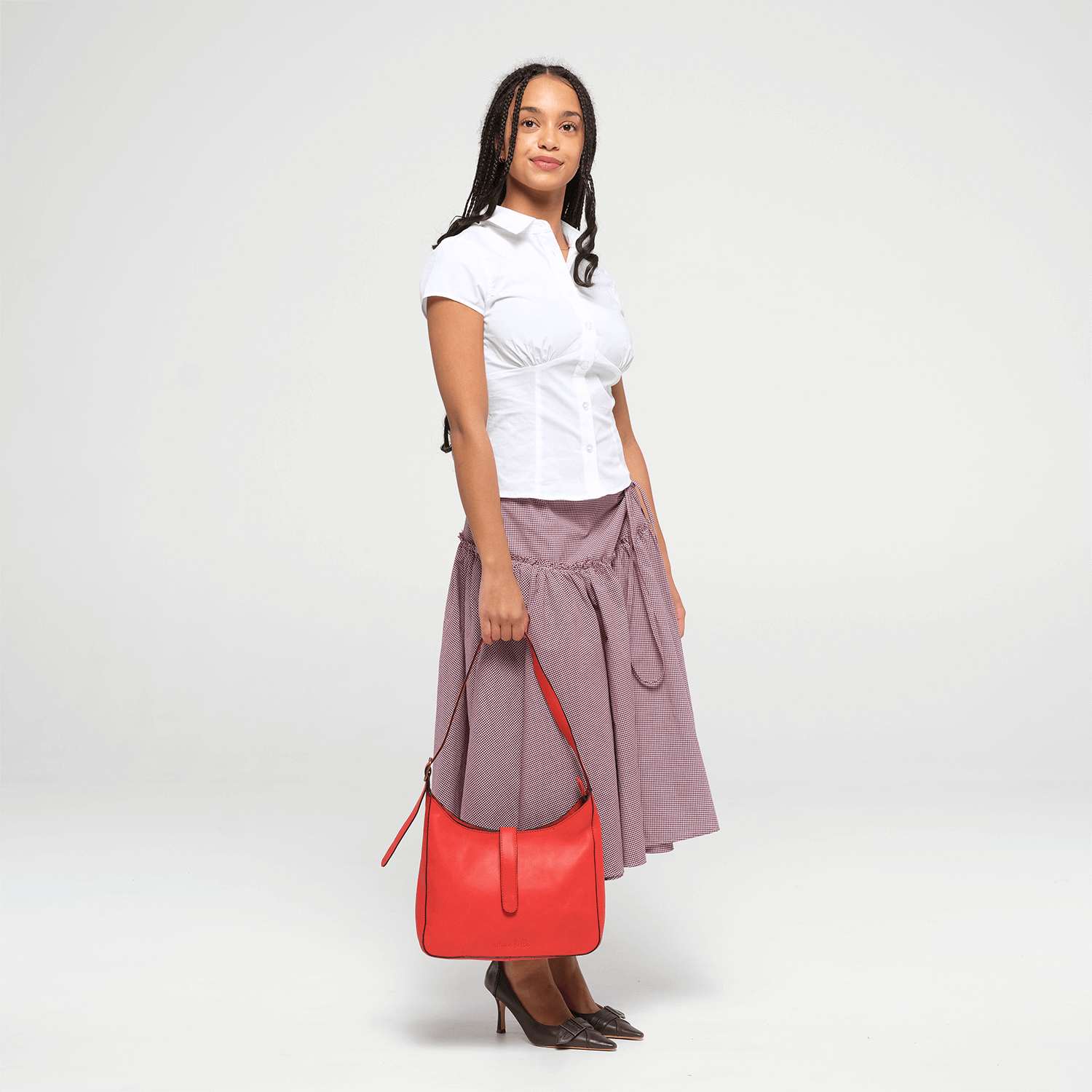 Woman holding a red leather shoulder bag  against a white background