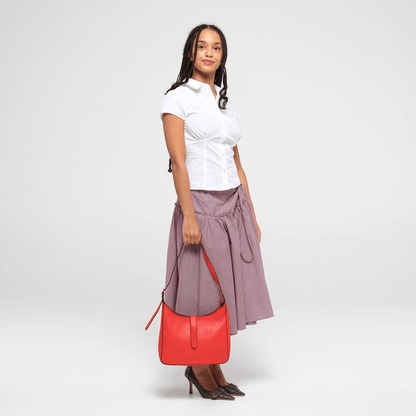 Woman holding a red leather shoulder bag  against a white background
